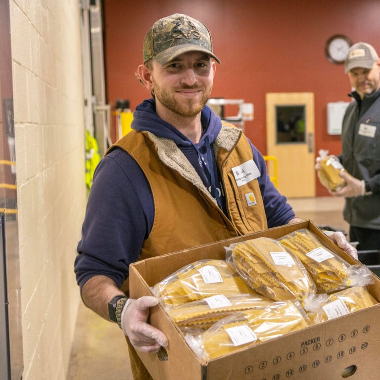 Blessings of Hope volunteer with a big box of pasta